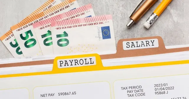 50 and 10 euro banknotes beside folders labelled Payroll and Salary with a payslip, a pen and a pencil