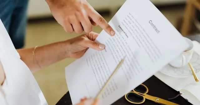 Business partners pointing to a “Commercial Terms” clause in a contract before signing