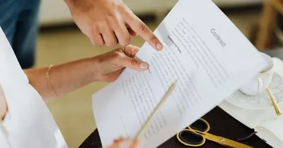 Business partners pointing to a “Commercial Terms” clause in a contract before signing