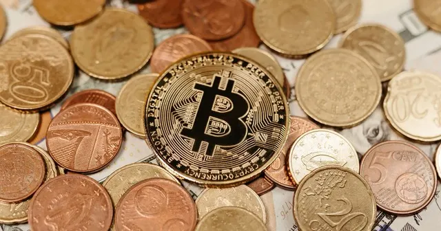 A bitcoin coin among coins and banknotes – cryptocurrency alongside money in commercial dealings
