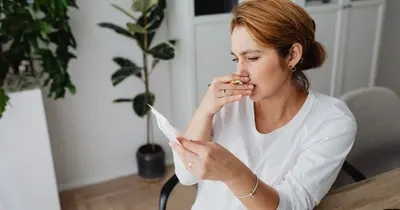 A woman reviewing an invoice at her desk with a worried expression, checking whether she owes payment for an online order