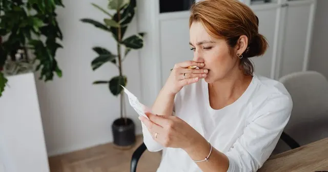 A woman reviewing an invoice at her desk with a worried expression, checking whether she owes payment for an online order